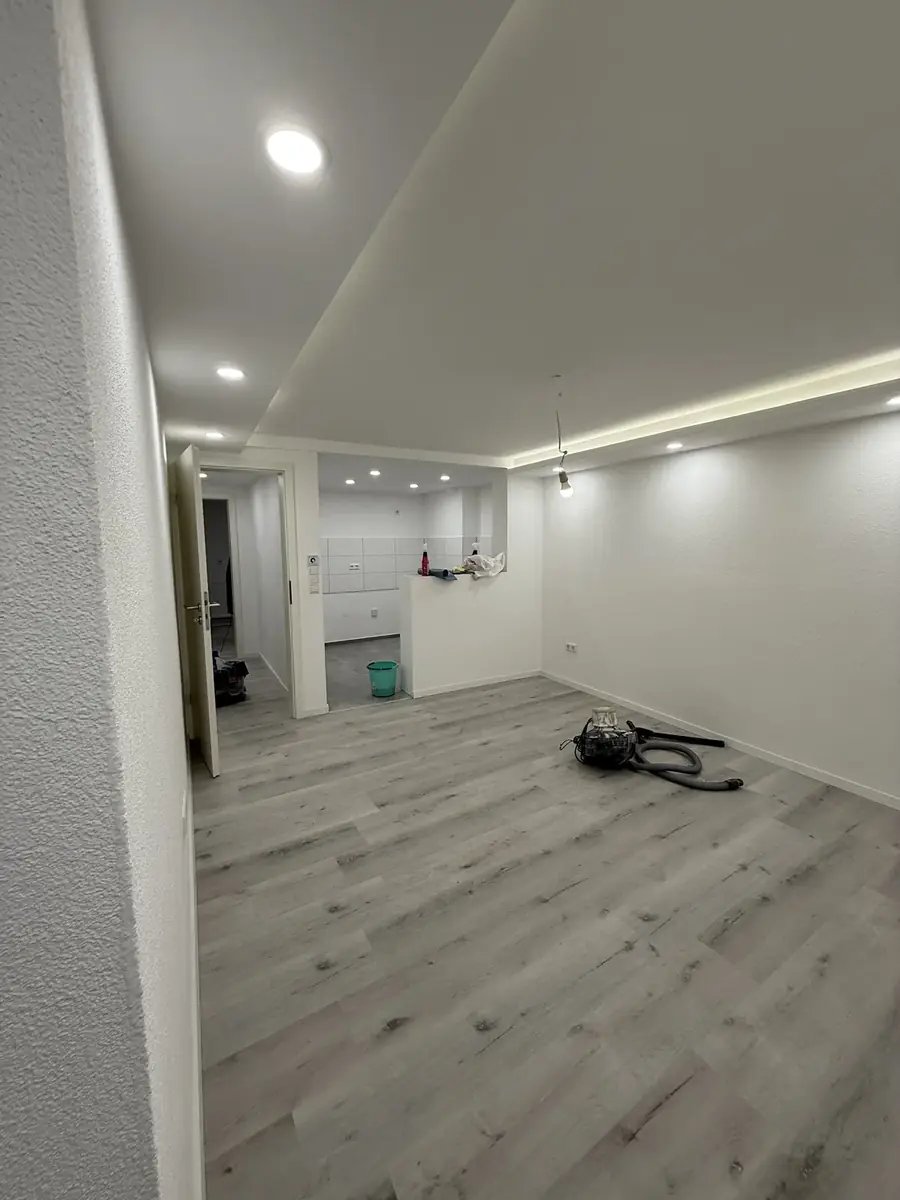 Fertiggestellter heller Wohnraum mit Lichtvoute, LED-Spots und Vinylboden in Holzoptik